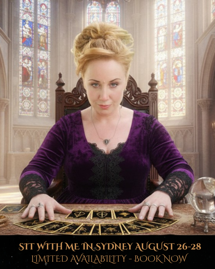 Talitha Marie Psychic Medium sits on a throne, clothed in a velvet purple dress in a gothic style parlour with tarot cards spread on a table